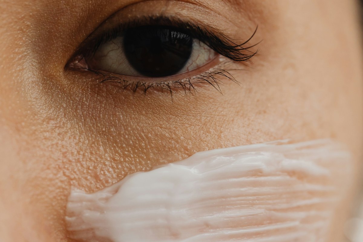 Close-up of a woman's eye and cheek with a swatch of face cream