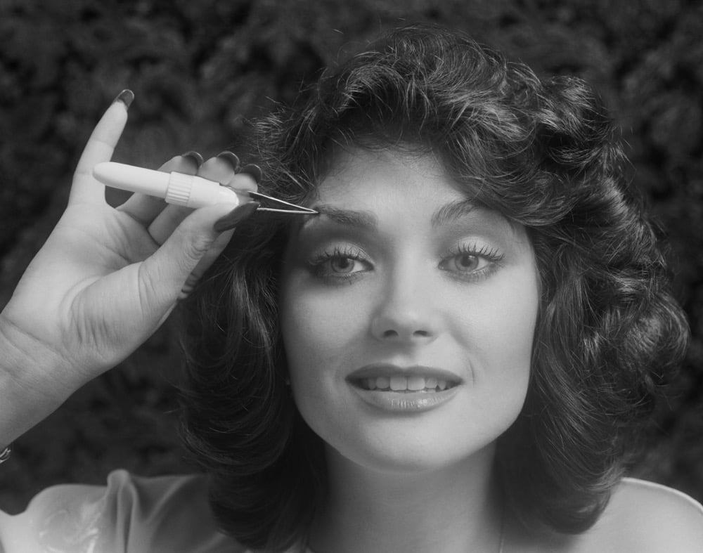 Vintage photo of a woman tweezing her eyebrows