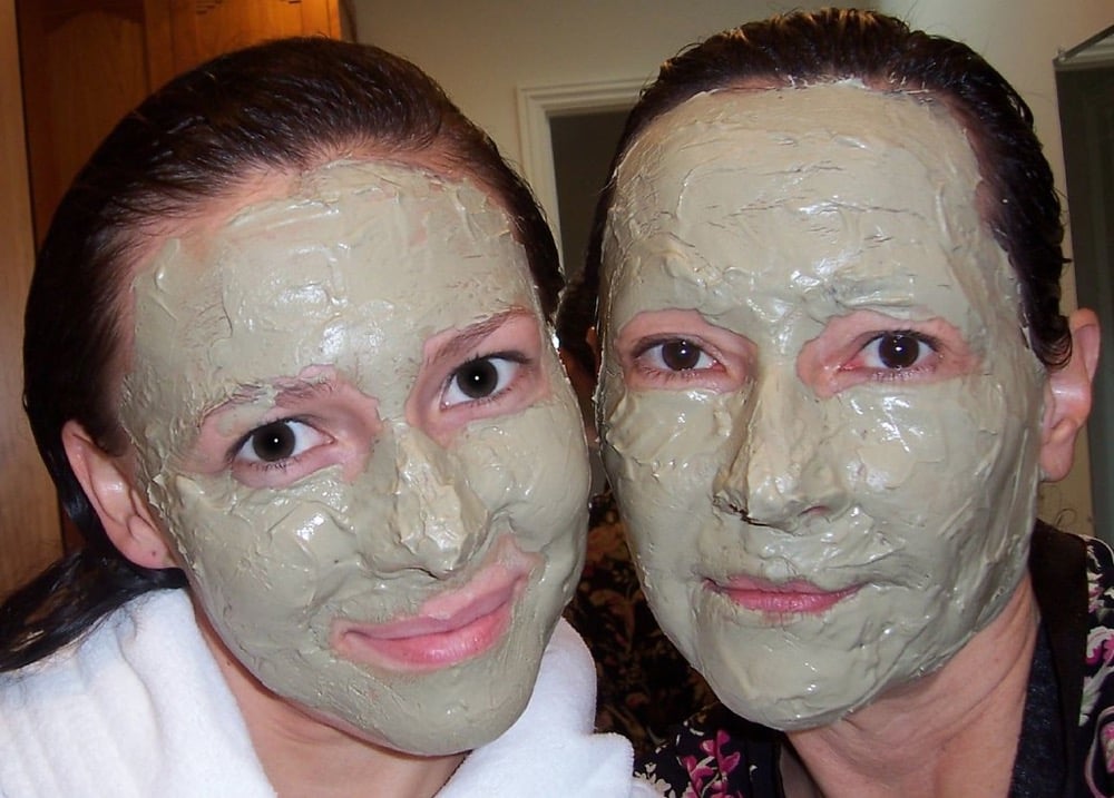 Two women wearing green clay mud masks