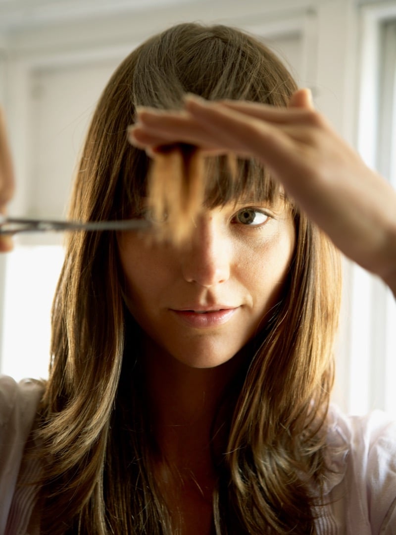 Woman trimming her bangs with scissors